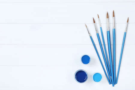 Colorful gouache paints and brushes on white wooden tableの写真素材