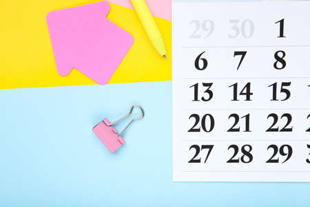 Calendar page with pen, clip and paper arrow on colorful backgroundの写真素材