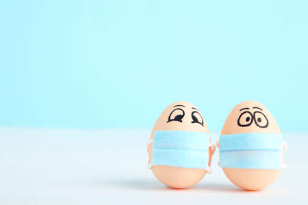 ? hicken eggs in medicine masks with funny faces on blue backgroundの写真素材