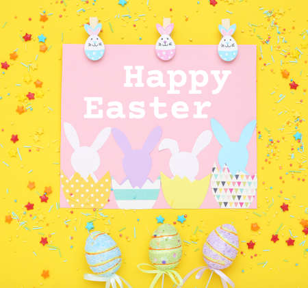 Easter concept. Greeting card with colorful eggs and sprinkles on yellow background