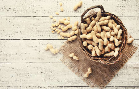 Peanuts in basket on white wooden tableの写真素材