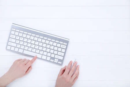 Female hands typing on computer keyboard and holding mouse on white backgroundの写真素材