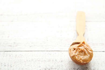 Peanut butter in spoon on white wooden table