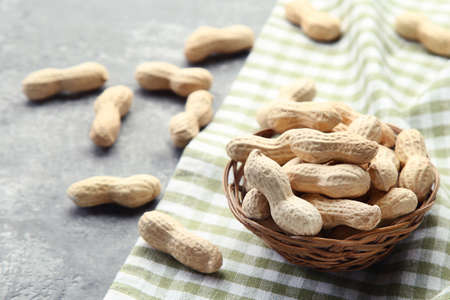Peanuts in basket on gray wooden table