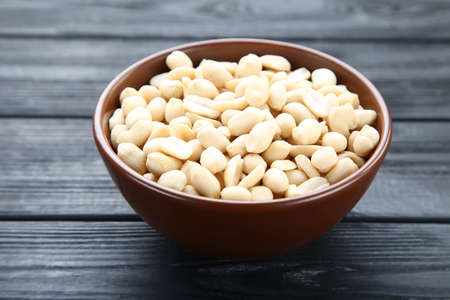 Peanuts in bowl on black wooden tableの写真素材