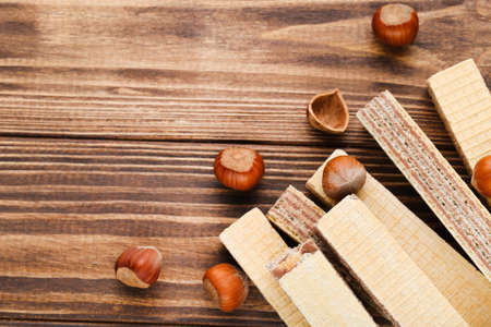 Wafer sticks with hazelnuts on brown wooden background