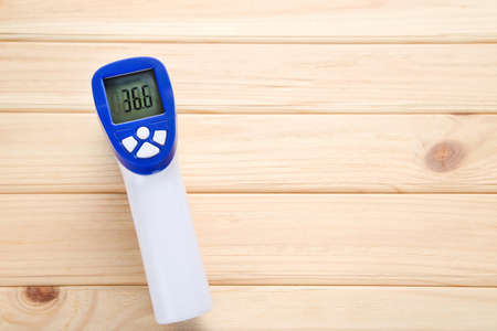 Digital infrared thermometer on wooden background
