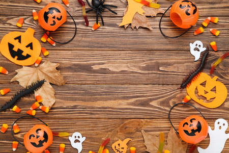 Halloween pumpkins, candies, spider and autumn leafs on brown wooden tableの写真素材