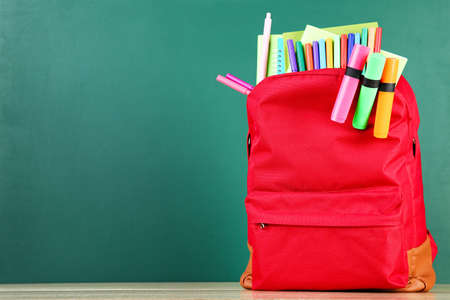 Backpack with school supplies on chalkboard backgroundの写真素材