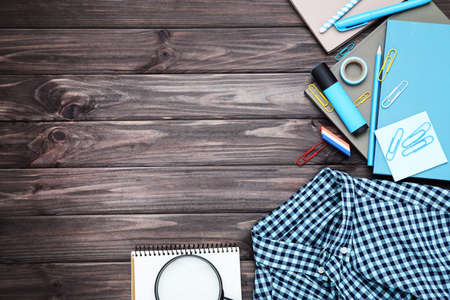 Different school supplies with shirt on wooden background