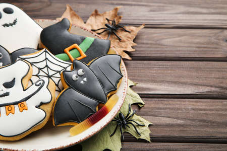 Halloween gingerbread cookies with spiders and dry leafs on wooden tableの写真素材