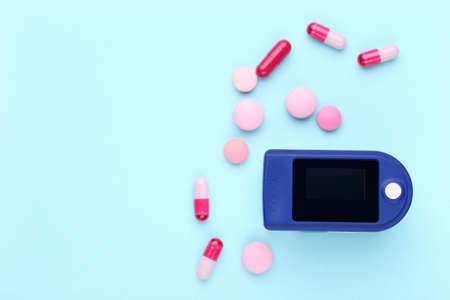 Pulse oximeter with pills on blue backgroundの写真素材