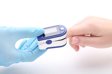 Doctor in glove performs pulse oximeter test on fingerの写真素材
