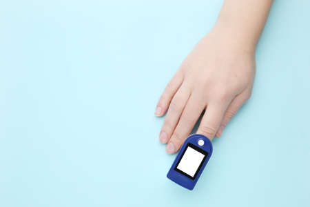 Pulse oximeter on finger on blue background
