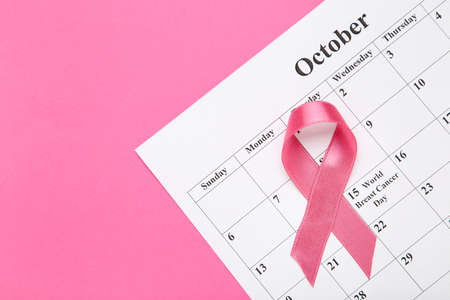 Cancer concept. Ribbon with white paper calendar on pink backgroundの写真素材