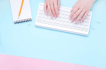 Female hands typing on computer keyboard with notepad and pencilの写真素材
