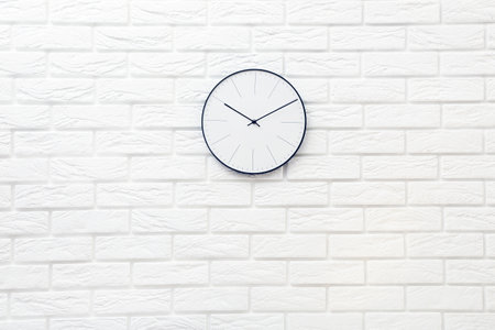Round clock on white brick wall background