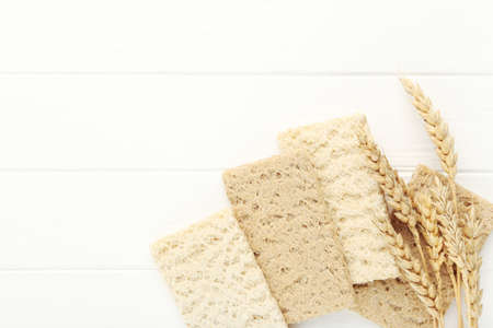Rye crispbread with wheat ears on white wooden table
