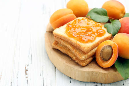 Apricots, toast with jam and green leafs on white backgroundの写真素材