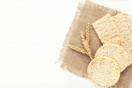 Rye crispbread with wheat ears on white wooden table