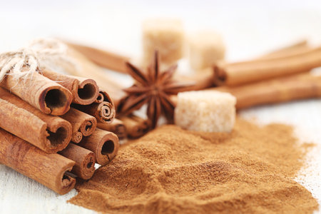 Cinnamon powder with sticks and sugar cubes on white wooden backgroundの写真素材