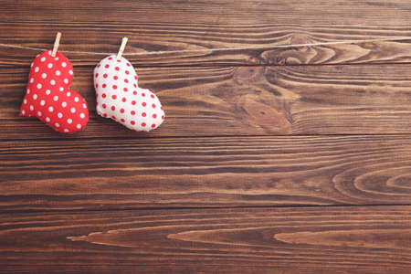 Fabric hearts hanging on rope on brown wooden backgroundの写真素材