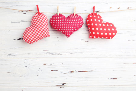 Fabric hearts hanging on rope on white wooden backgroundの写真素材
