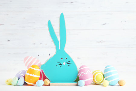 Wooden rabbit and colorful easter eggs on white backgroundの写真素材