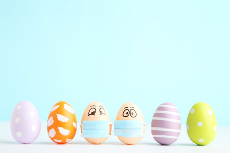 Row colorful easter eggs painted and in medical mask with funny faces on blue backgroundの写真素材