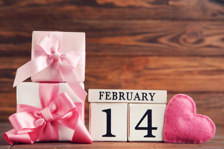 Gift boxes with fabric heart and cube calendar on brown wooden backgroundの写真素材