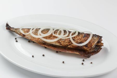 Grilled mackerel with onions on a white dish