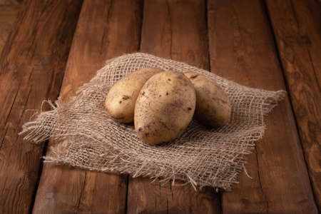 Eco vegetables - yellow potatoes on a wooden background, vegan foodの写真素材
