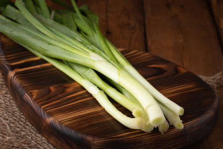 Eco vegetables - fresh green onions on wooden background, vegan foodの写真素材