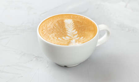 White cup of hot cappuccino coffee on concrete background