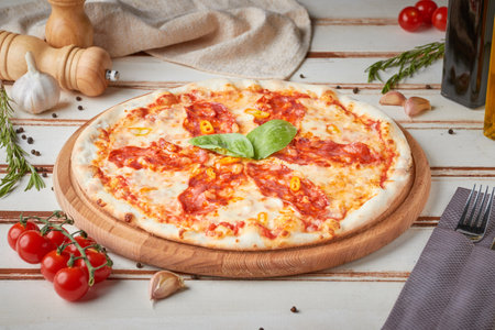 Pizza with slices, sauce and herbs, wooden white backgroundの写真素材