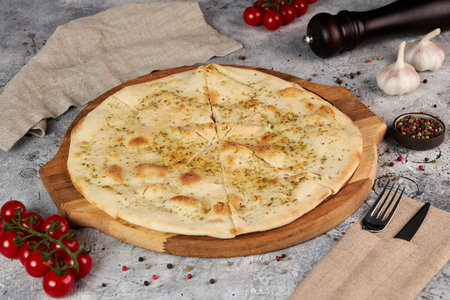 Focaccia with garlic and oregano on a wooden board, gray backgroundの写真素材