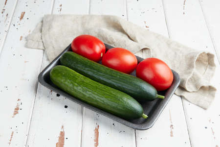 Fresh cucumbers and tomatoes on a wooden white backgroundの写真素材