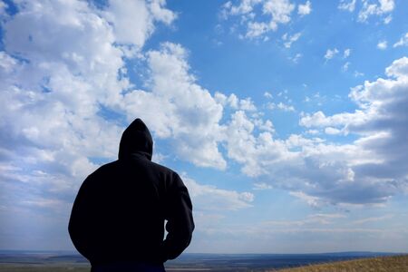 Loneliness. Man is one all over the world. Man on a background of cloudy sky and fields.