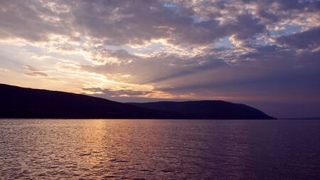Landscape. Nature. Sunset on the river. Shore with mountains. The lights of a sun. Beautiful sky.の写真素材