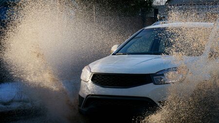 Spring. Mud. The car is driving at high speed in a puddle. Spray scattered around.の写真素材