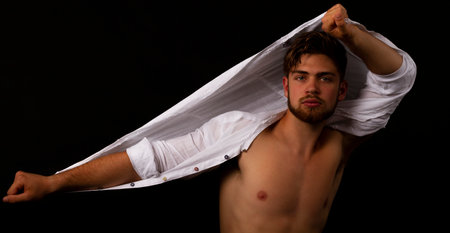Handsome young man with shirt isolated on blackの写真素材
