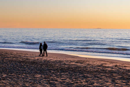 Seaside of Viareggio at sunset, with islands in the distance and couple walking, Tuscany, Italy