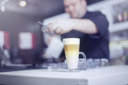 Barista prepares cappuccino in his coffee shop. Close-up cup of coffee.の写真素材