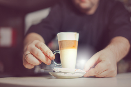 Barista prepares cappuccino in his coffee shop. Close-up cup of coffee.の写真素材
