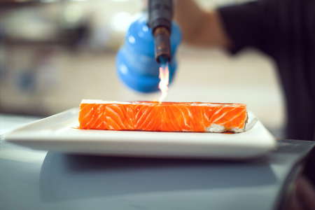 chef using a torch burn on Miso sauce - Salmon Saikyo sushi.の写真素材