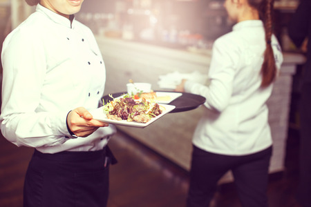 Waiters carrying plates with meat dish at a wedding.の写真素材