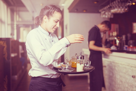 woman working as waitress holding a tray with tea and coffee.の写真素材