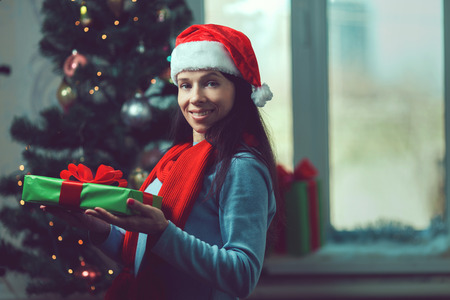 Beautiful young woman in a room decorated for Christmas and smiles.の写真素材