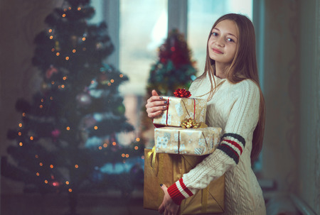 Beautiful young woman in a room decorated for Christmas and smiles.の写真素材