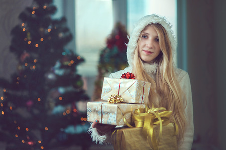 Beautiful young woman in a room decorated for Christmas and smiles.の写真素材